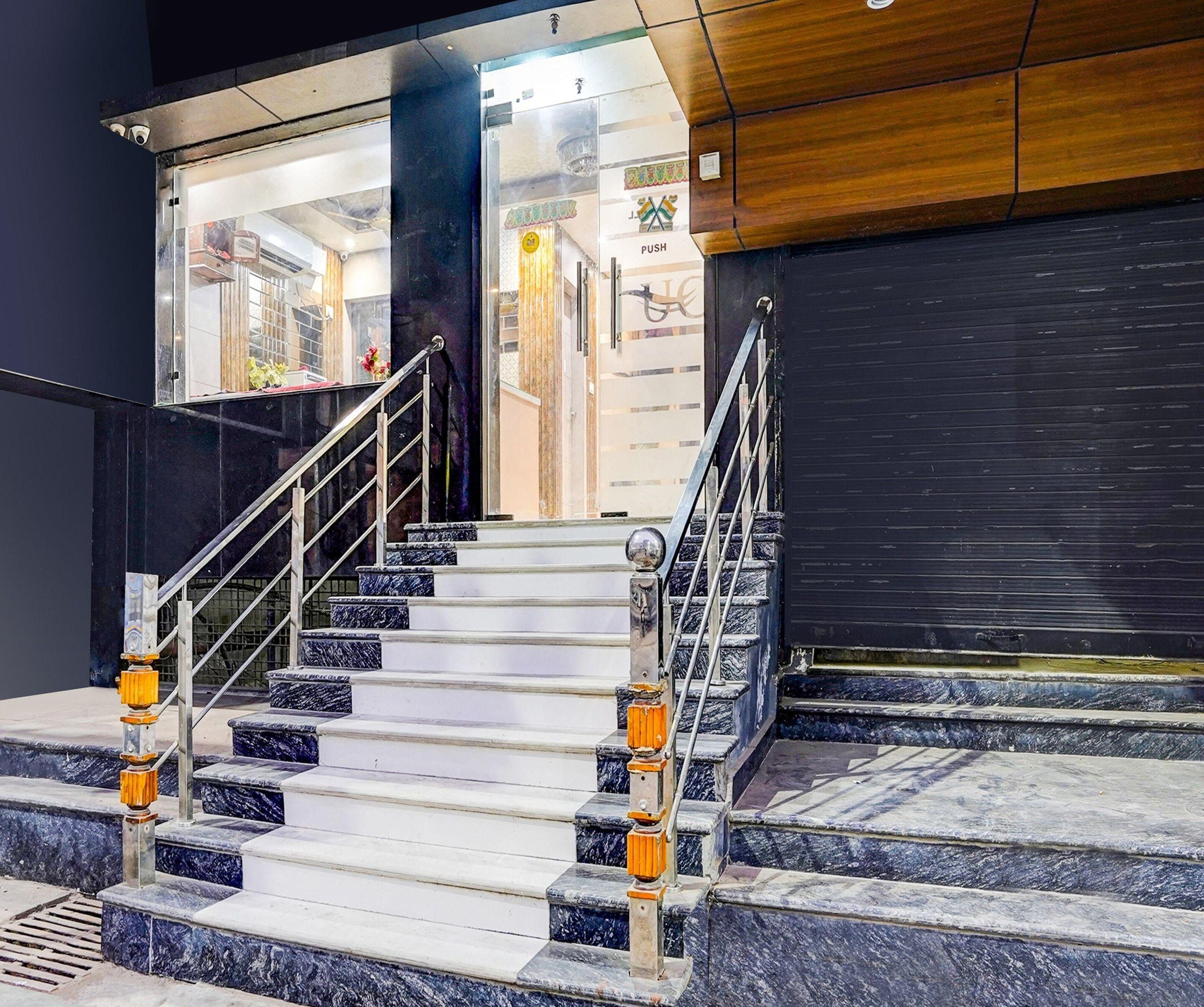A staircase with marble steps and metal railings leading to a glass door entrance.