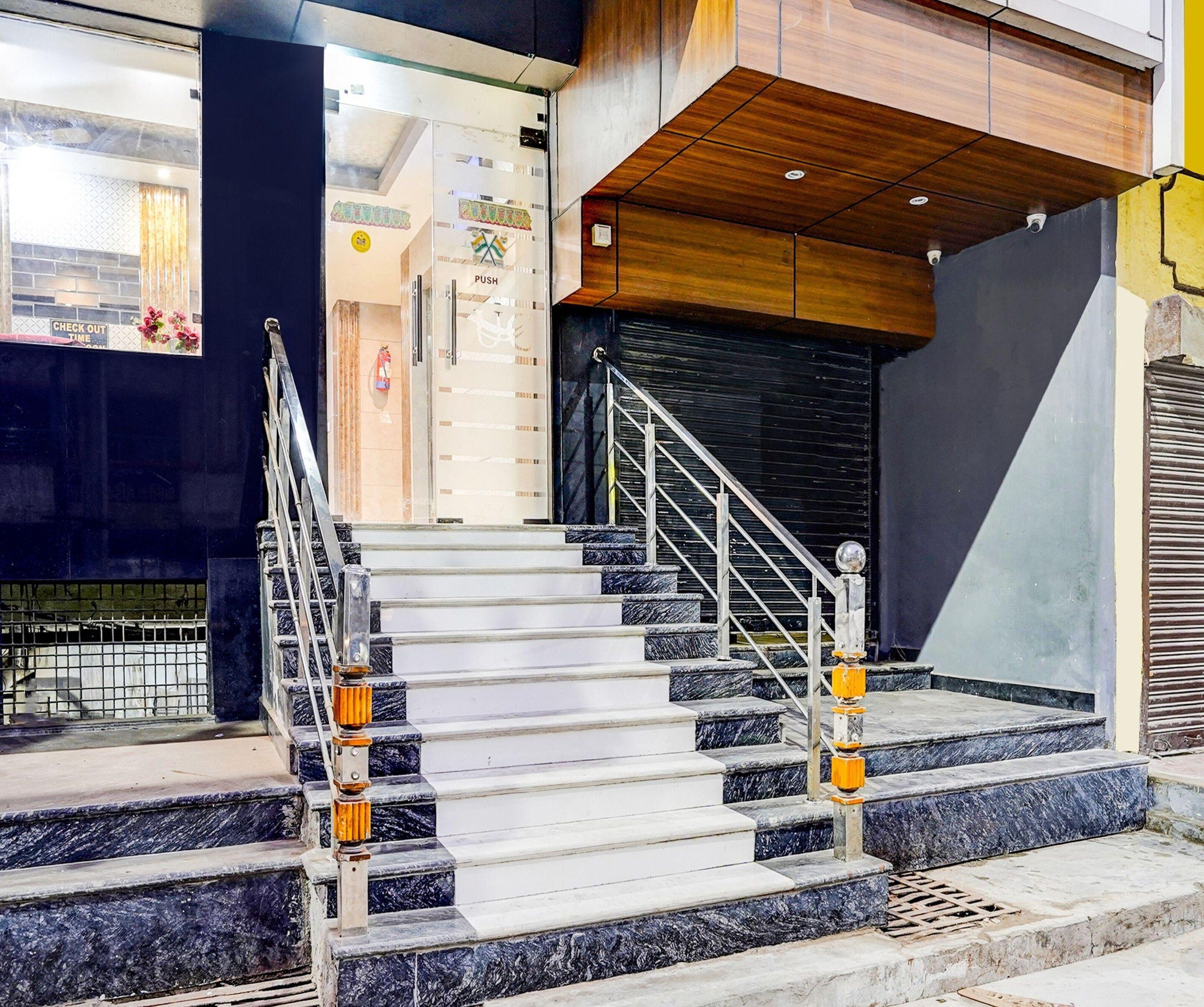 Una escalera con escalones de mármol y barandillas metálicas, que conduce a un techo de madera y un persiano negro cerrado.
