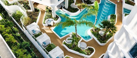 A multi-level hotel with a central swimming pool, outdoor seating areas, and lush landscaping.