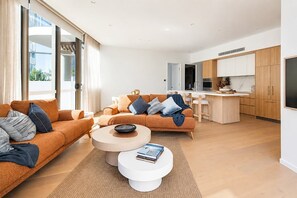 Ein modernes Wohnzimmer mit einer Sofagarnitur, einem Couchtisch und einer Küchenzeile mit Schränken und einer Arbeitsfläche.