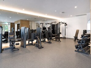 Een moderne sportschool met diverse trainingsapparaten, waaronder krachttoestellen en losse gewichten.