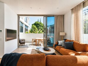 A modern living room with a sofa, coffee table, and a flat-screen TV. - Sunset Resort Escape - Spacious 3 Bedroom (Main Beach)