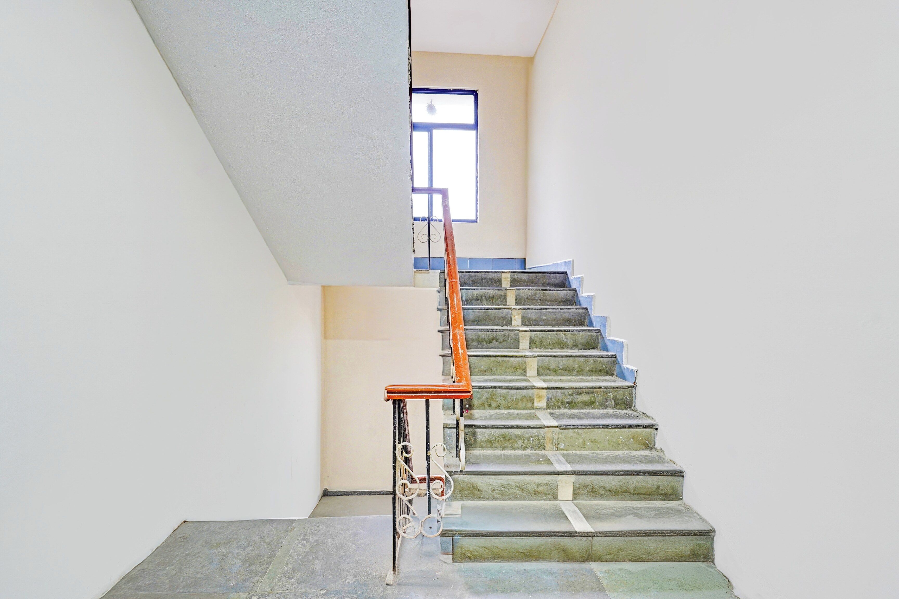 Eine Treppe mit Metallgeländer und Holzhandlauf, die zu einer Empore mit einem Fenster führt.