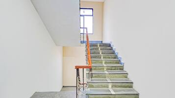 A staircase with a metal railing and a wooden handrail, leading to a landing with a window.