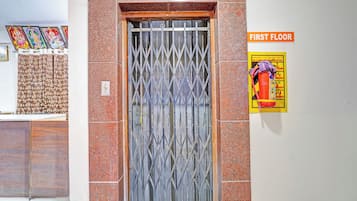 A metal gate with a diamond pattern, a sign indicating the first floor, and a fire safety poster on the wall.