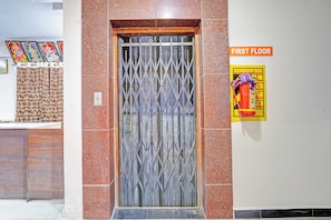 Una reja metálica con un diseño de rombos, un letrero que indica el primer piso y un cartel de seguridad contra incendios en la pared.