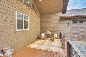 A covered outdoor area with wooden flooring, two wicker chairs, a small table, and a potted plant. - Golfer’s Oasis! Ponderosa Pine Retreat in Show Low (Show Low)