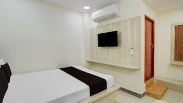 Habitación de hotel con una cama, televisor montado y una puerta de madera.