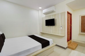A hotel room with a bed, a mounted television, and a wooden door. - Hotel O Saibaba Temple Chintal (Hyderabad)