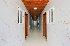 Un pasillo con paredes de mármol blanco, puertas de madera y techo de madera.