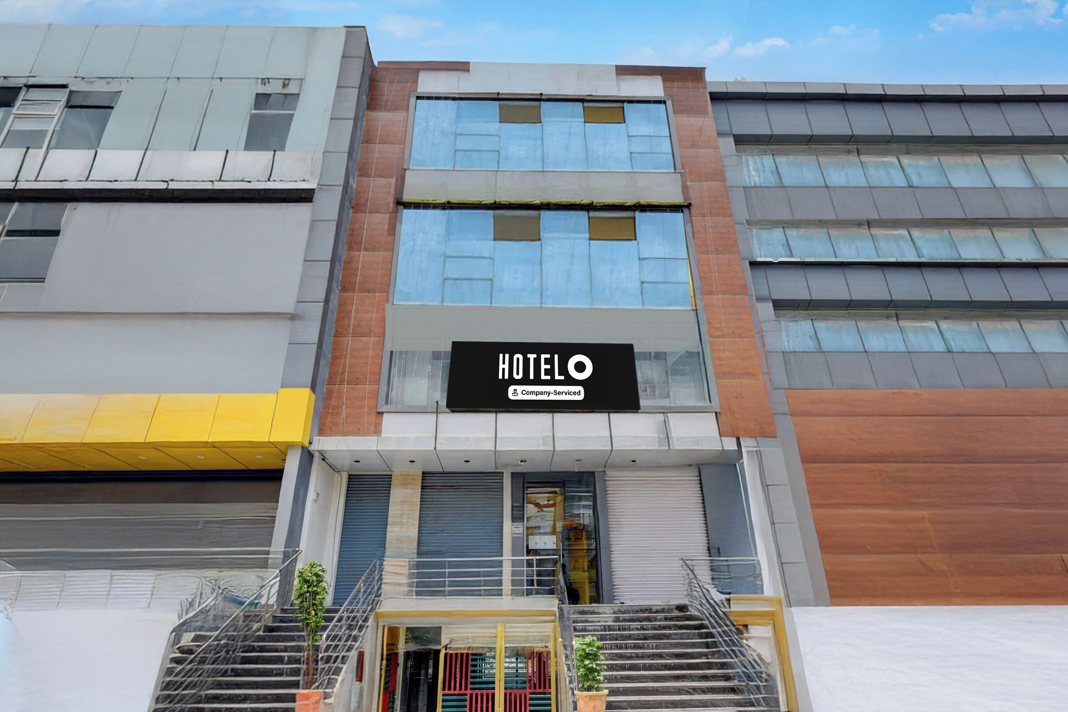 Un hotel con fachada moderna, un letrero llamativo y una escalera que conduce a la entrada.