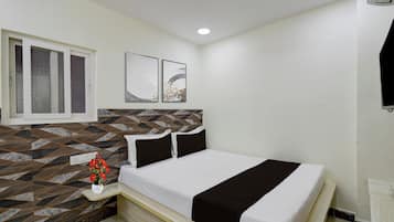Un dormitorio con cama, mesita de noche, una obra de arte en la pared, una ventana y un papel tapiz estampado.