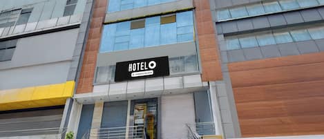 Un hotel moderno con un llamativo letrero que dice 'HOTEL', una escalera que conduce a la entrada y una vista despejada del cielo.