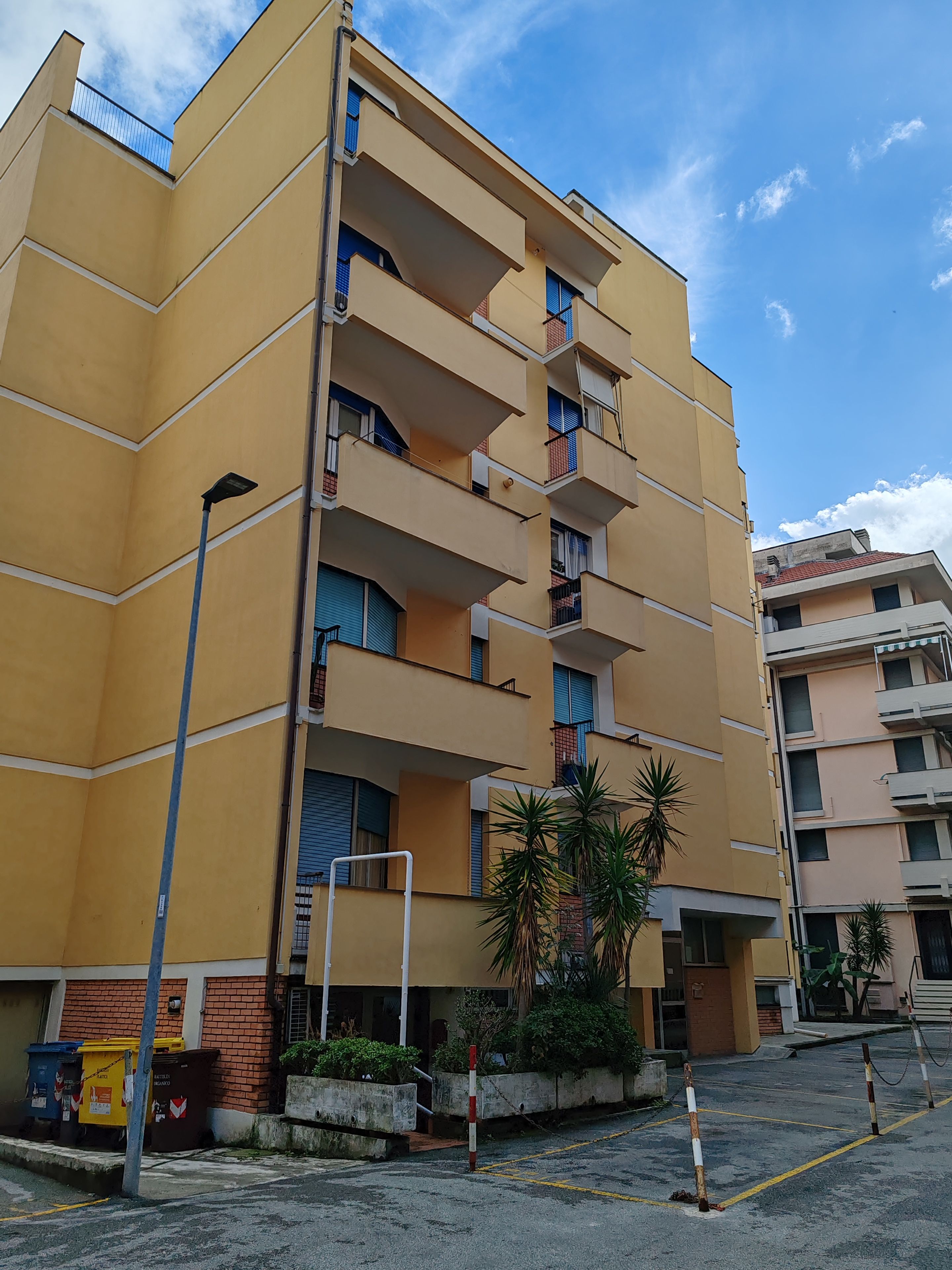 Un edificio de varios pisos con balcones y un estacionamiento al frente.