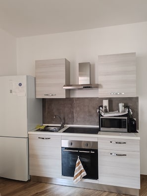 A modern kitchen with a built-in oven, microwave, and stainless steel sink.