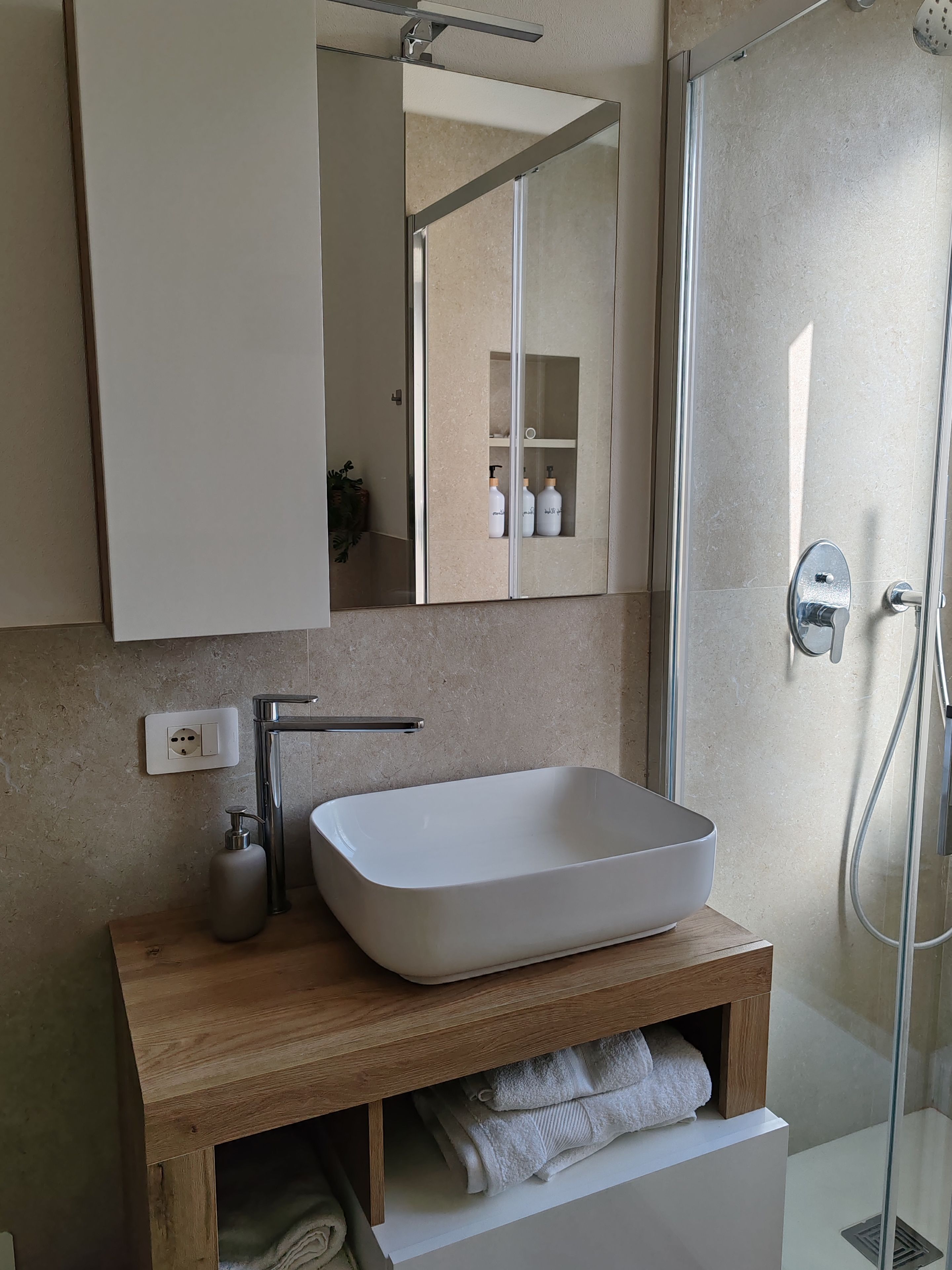 Ein modernes Badezimmer mit einem rechteckigen Waschbecken, einem Spiegel und einer Duschkabine.