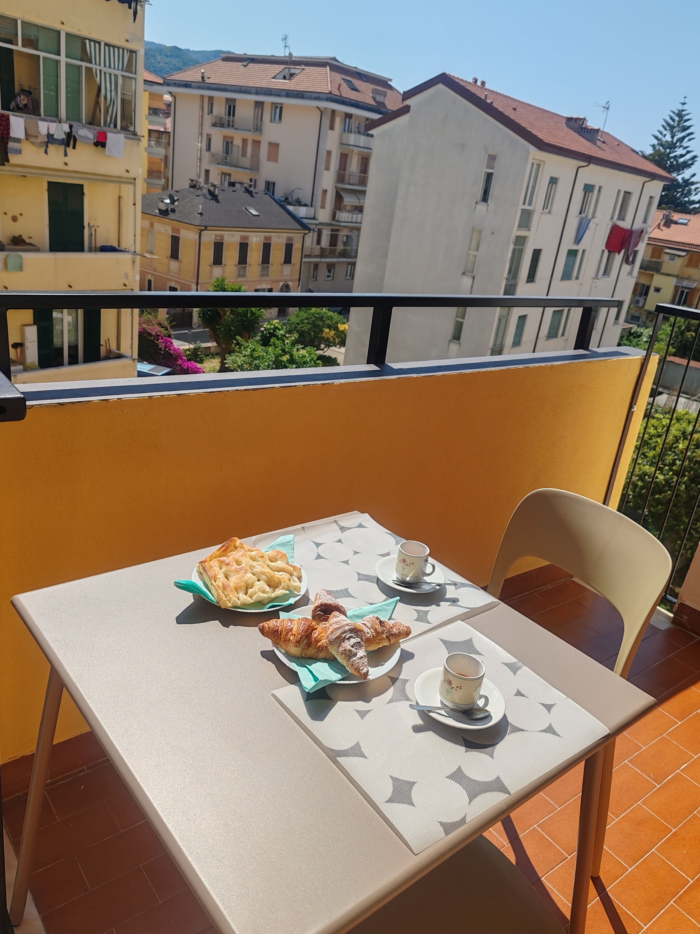 Ein Balkon mit einem Tisch für zwei Personen, gedeckt mit Speisen und Getränken.