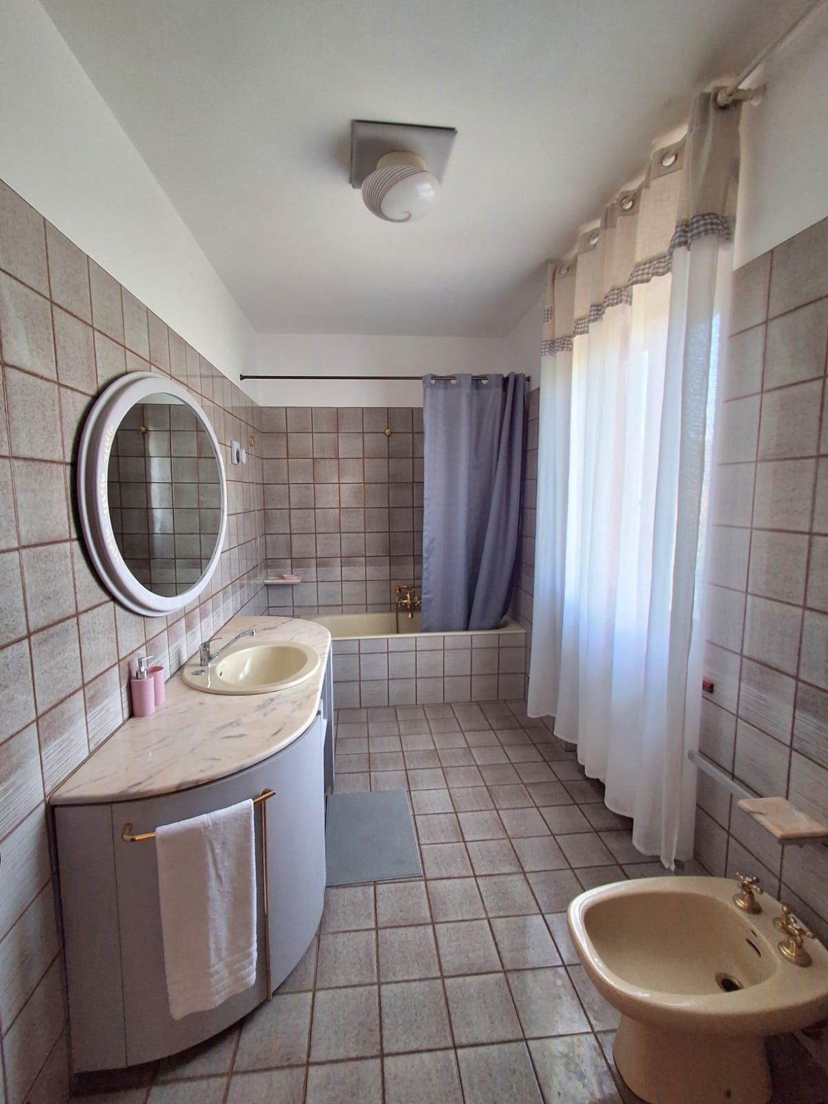 Une salle de bain équipée d’un lavabo, d’un miroir, d’une baignoire et d’un rideau de douche.