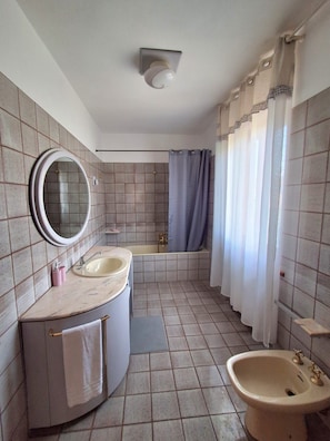 A bathroom with a sink, mirror, bathtub, and shower curtain. - New Listing (Marche)