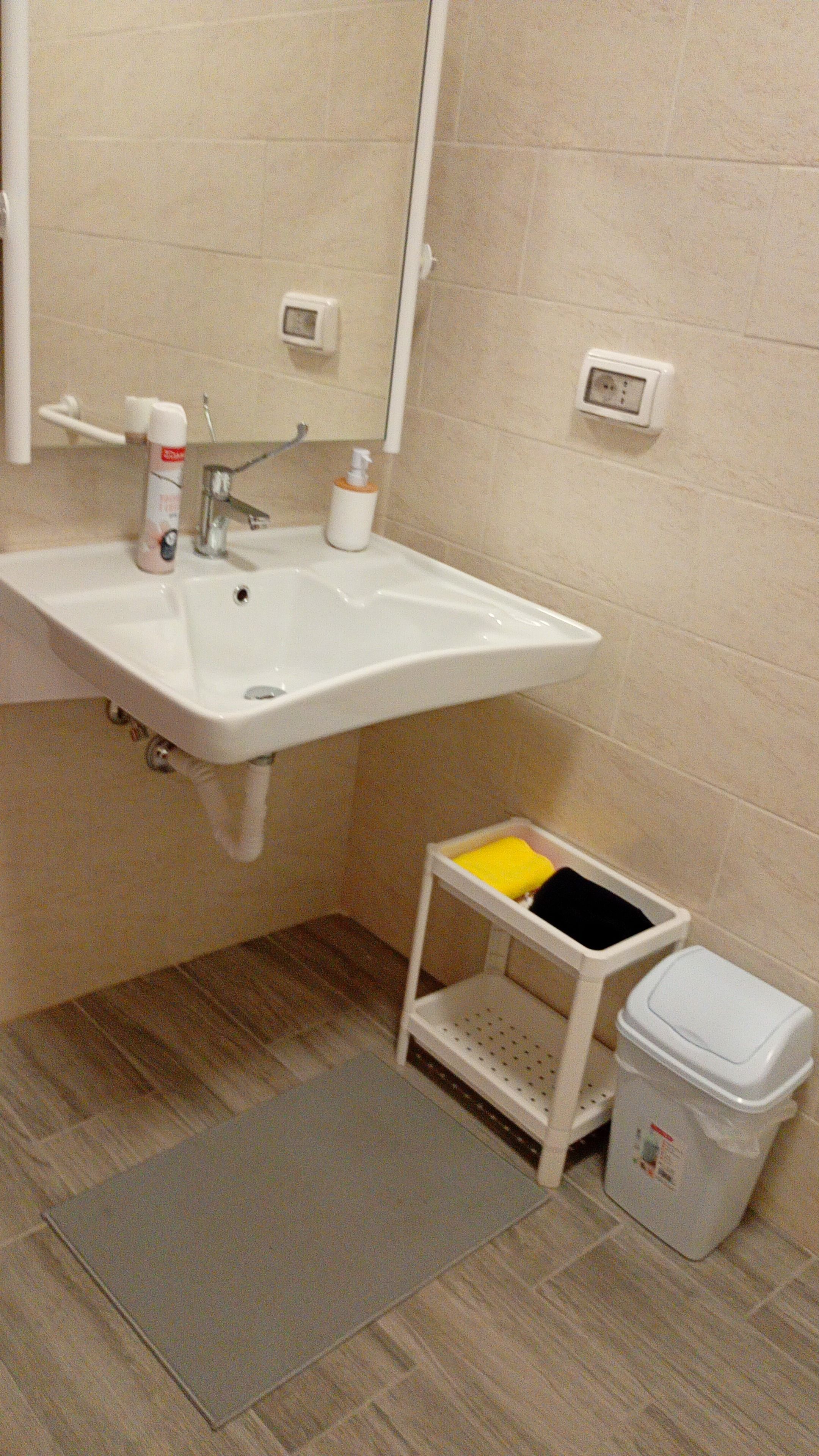 Une salle de bain équipée d’un lavabo, d’un miroir, de toilettes et d’une étagère de rangement.