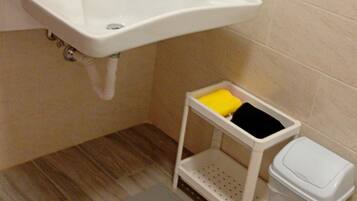 Une salle de bain équipée d’un lavabo, d’un miroir, de toilettes et d’une étagère de rangement.