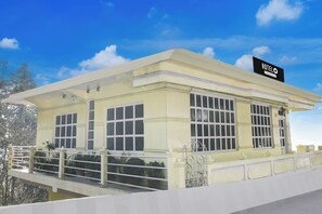 A hotel building with a flat roof, large windows, and a balcony with railings.