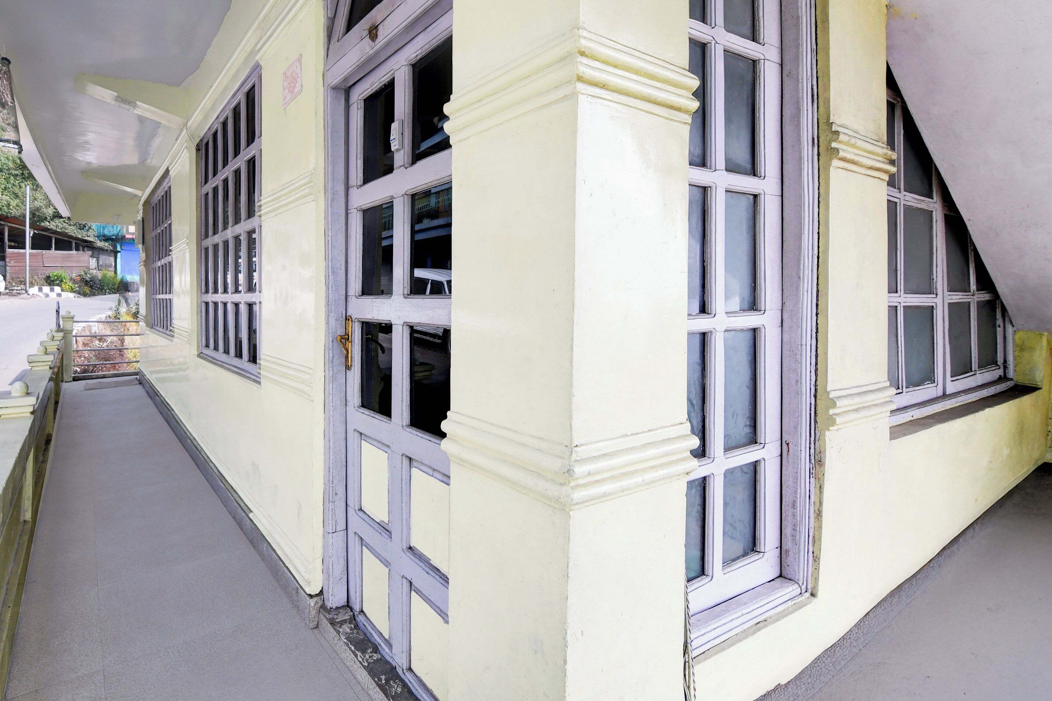 A corridor with a yellow building, large windows, and a staircase.