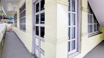 A corridor with a yellow building, large windows, and a staircase.