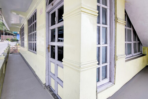 A corridor with a yellow building, large windows, and a staircase.
