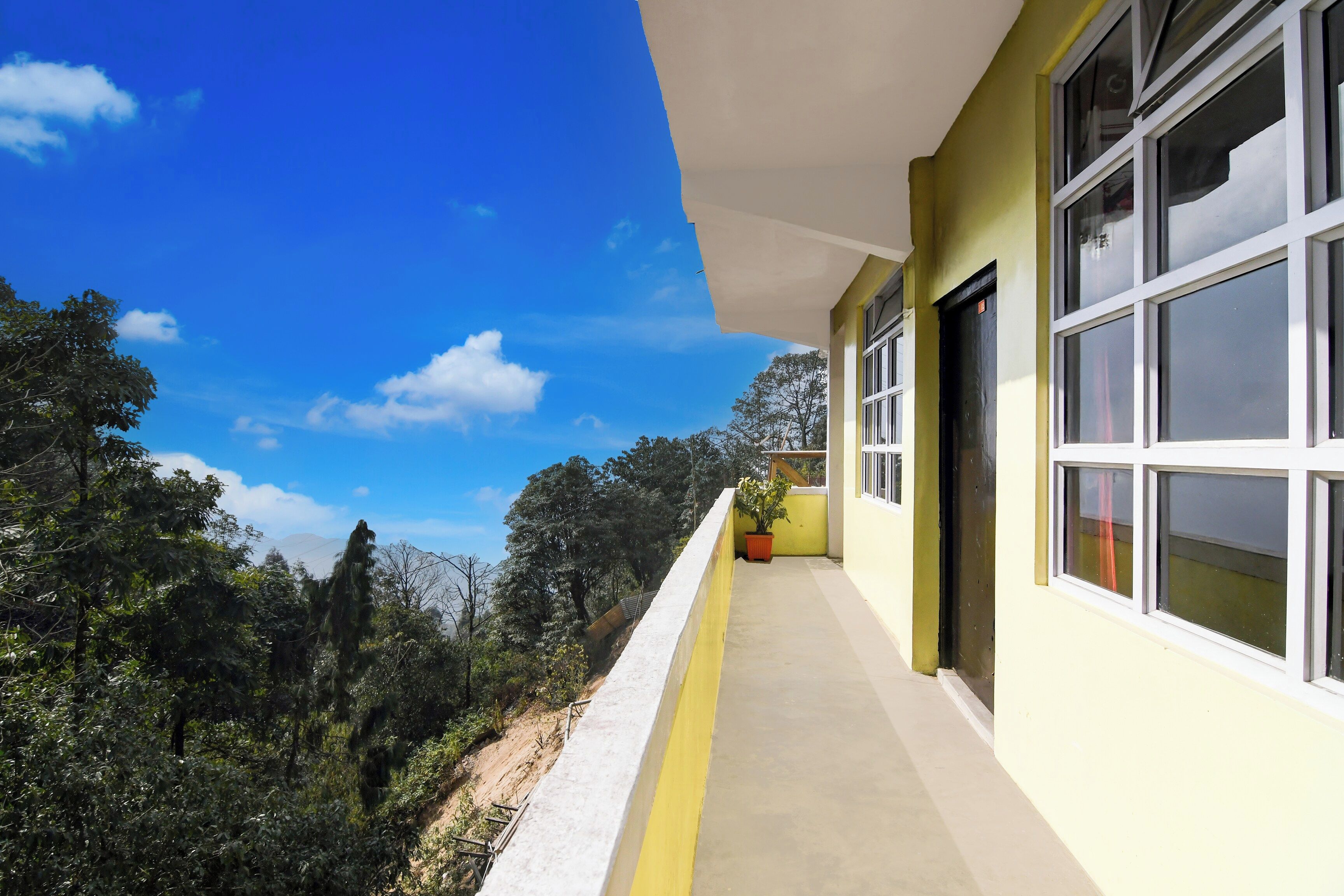 A building with large windows and a balcony overlooking a forested area.