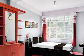 Une chambre à coucher comprenant un lit, un bureau, une chaise, une armoire, une fenêtre avec des rideaux et des œuvres d’art murales.