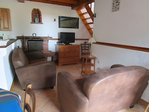 Una sala de estar con chimenea, televisor y comedor con mesa y sillas.
