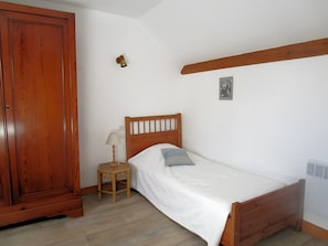 Un dormitorio con una cama de madera, una mesita de noche con lámpara, un armario de madera y una lámpara de pared.