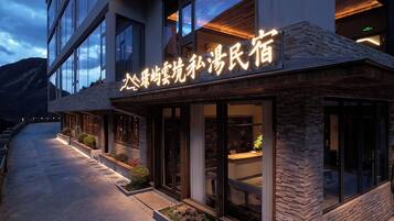 Um hotel com fachada de pedra e grandes janelas, exibindo uma placa com caracteres chineses.