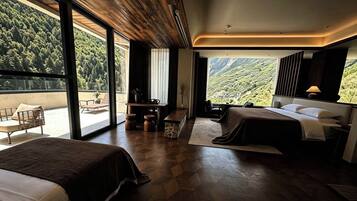 Habitación de hotel con dos camas, un escritorio y vista a una montaña boscosa.
