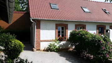 Une maison avec un toit recouvert de tuiles rouges, des murs en briques et une petite fenêtre.