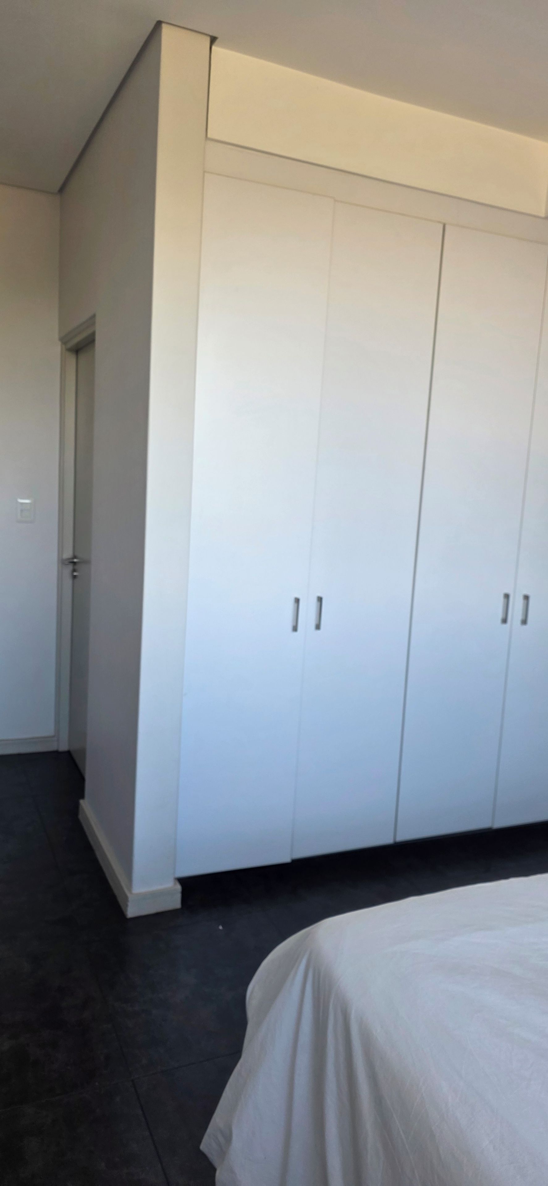 Une chambre à coucher avec une grande armoire, un lit et une porte donnant sur une autre pièce.