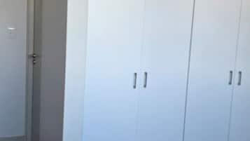 Ein Schlafzimmer mit großem Kleiderschrank, einem Bett und einer Tür zu einem anderen Raum.