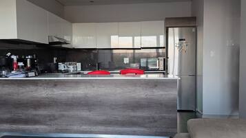 A modern kitchen with a central island, stainless steel appliances, and a large refrigerator.