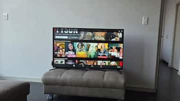 Ein Flachbildfernseher an der Wand mit einer Auswahl an Streaming-Inhalten.