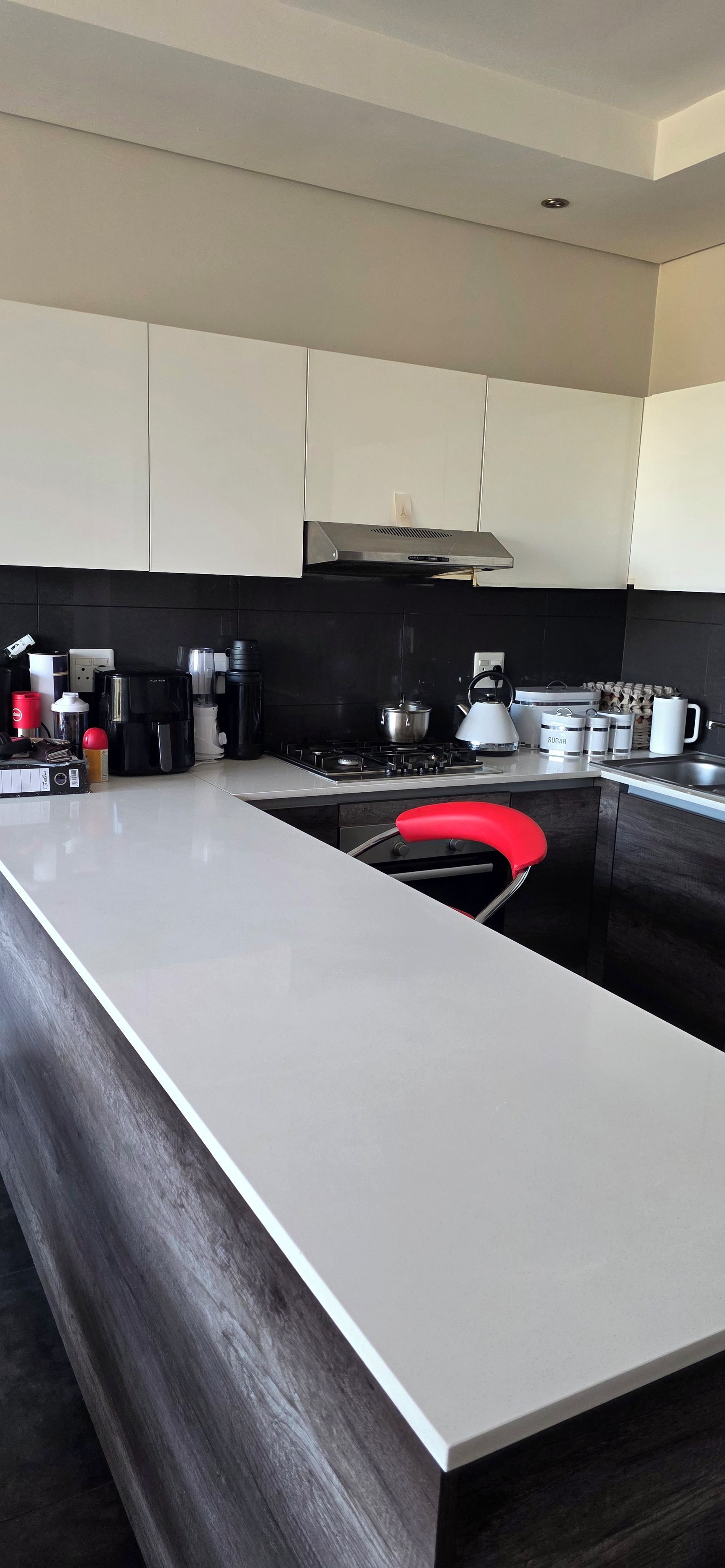 Une cuisine moderne dotée d’un grand îlot central, de plans de travail noirs et d’appareils électroménagers en acier inoxydable.