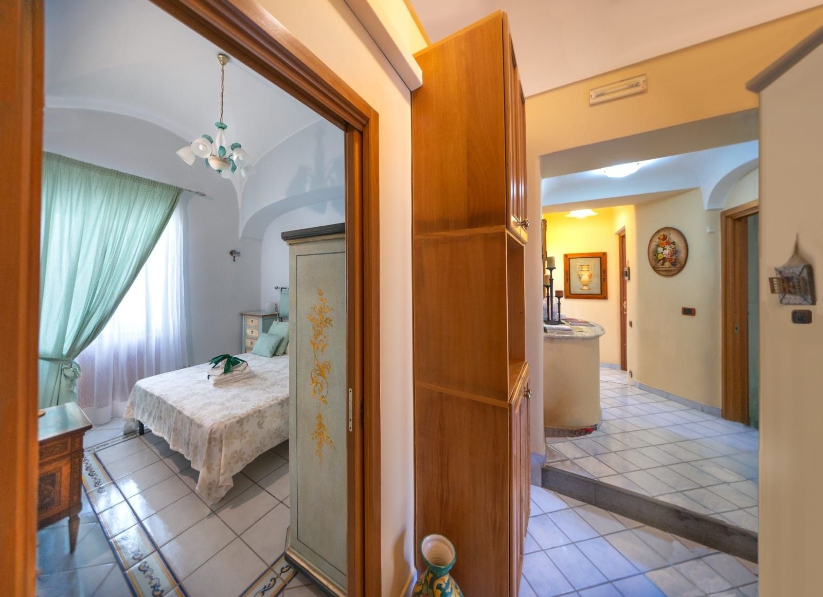 Ein Hotelzimmer mit einem Bett, einem Kleiderschrank, einem Badezimmer mit Waschbecken und einem Flur, der zu einem weiteren Zimmer führt.