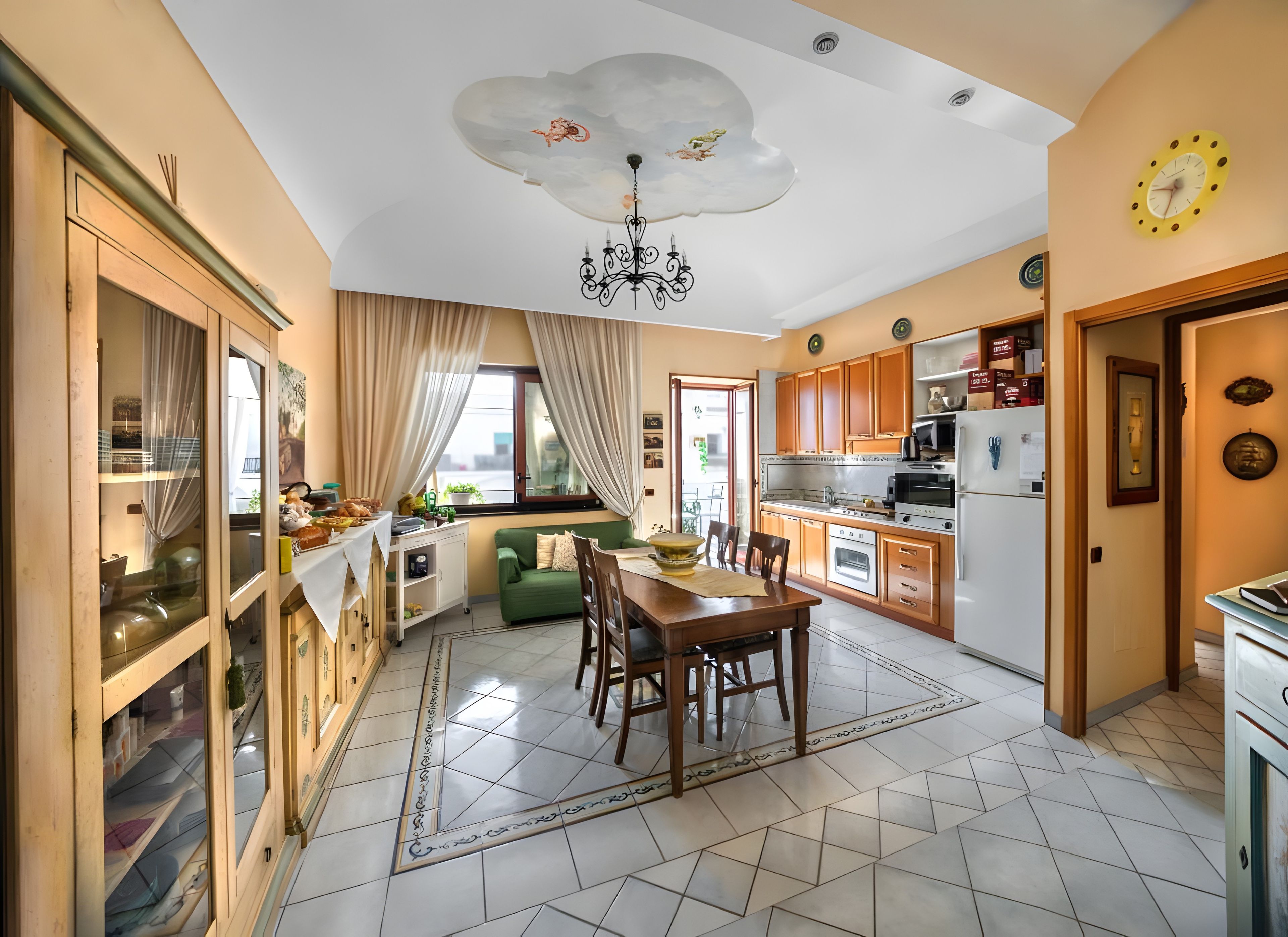 A modern kitchen with a dining area, a chandelier, and a clock on the wall.