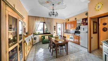 A modern kitchen with a dining area, a chandelier, and a clock on the wall.