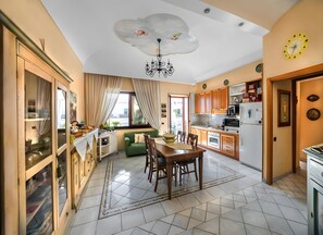 Eine moderne Küche mit Essbereich, einer Chandelüster und einer Wanduhr.