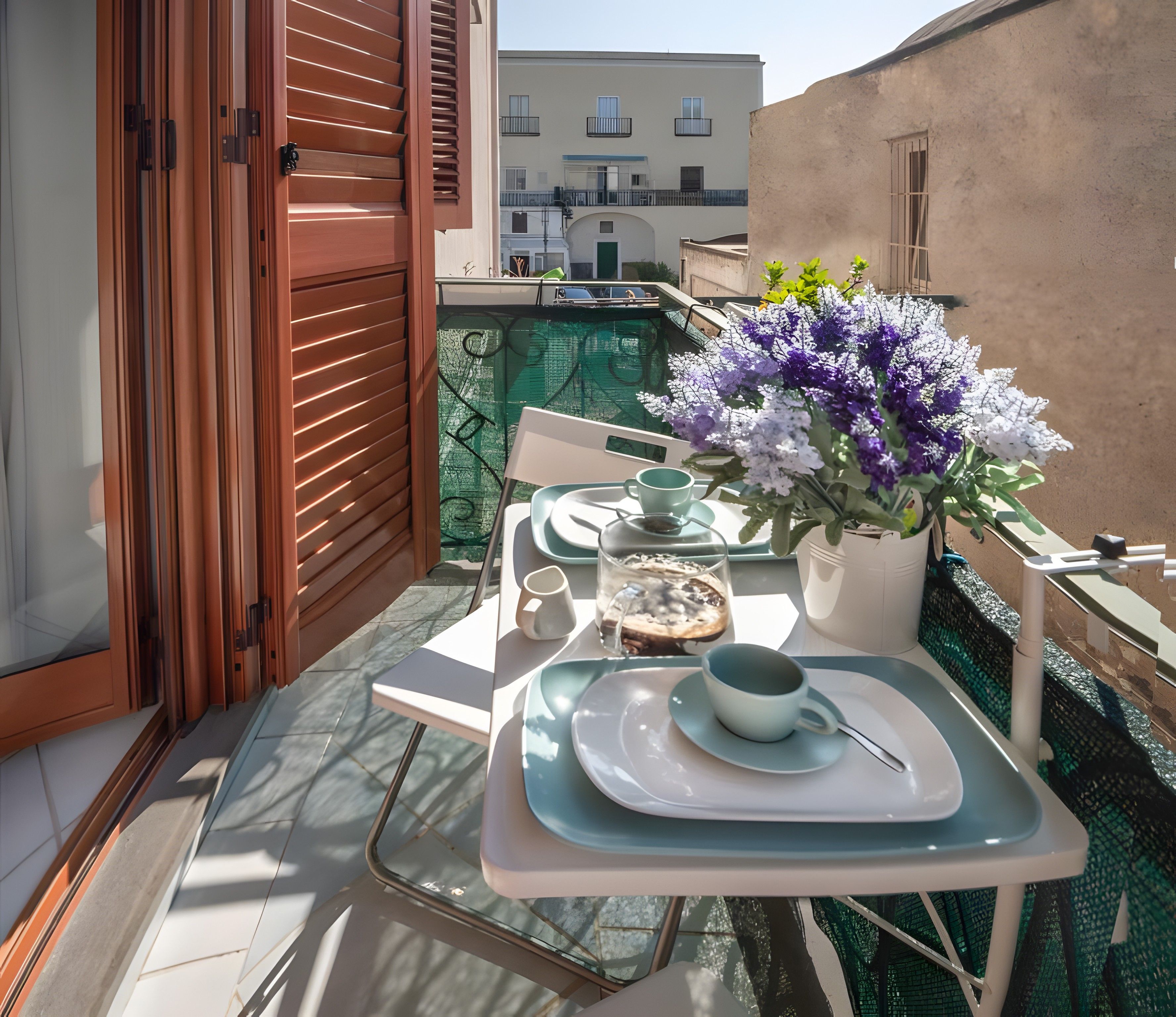 Ein Balkon mit einem Tisch für zwei Personen, einem Blumentopf und Blick auf Gebäude im Hintergrund.