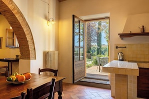A dining area with a table set for two, a radiator, and a view of the outdoors. - Croce di Bibbiano, San Gimignano View (Bibbiano)