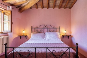 A bed with a metal frame, two bedside tables with lamps, a window with a view, and a radiator. - Croce di Bibbiano, San Gimignano View (Bibbiano)
