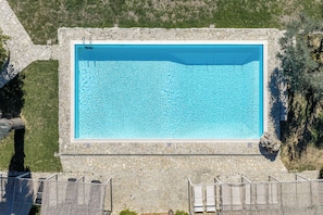A rectangular swimming pool with a stone border, surrounded by a stone wall and a wooden fence. - Croce di Bibbiano, San Gimignano View (Bibbiano)