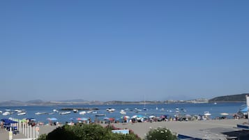 Une zone côtière avec des bateaux, des parasols et des gens sur la plage.